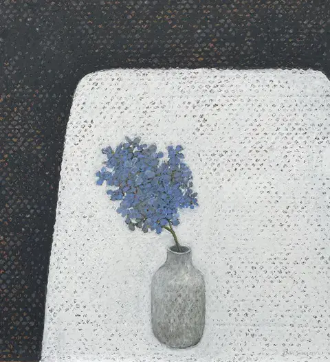 single branch of hydrangea flowers in a grey vase on a white table